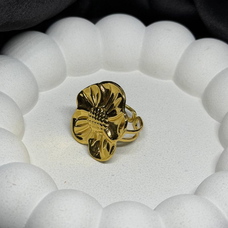 Gold ring with a textured design on a white beaded bracelet
