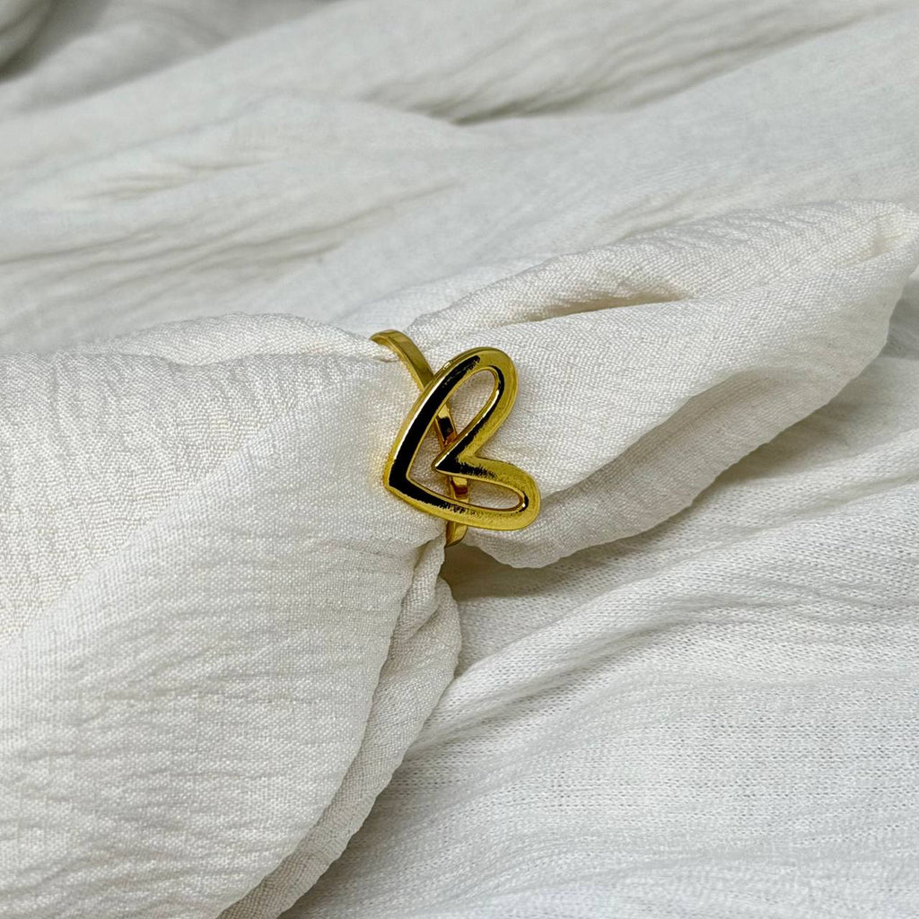 Gold ring with a heart design on a white fabric background
