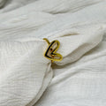Gold ring with a heart design on a white fabric background