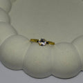 Gold ring with a diamond on a textured white surface