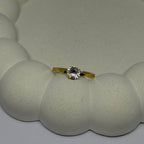 Gold ring with a diamond on a textured white surface
