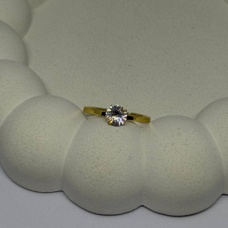 Gold ring with a diamond on a textured white surface